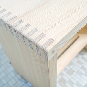 Close-up of a Japanese hinoki wood bath stool, showcasing precise joinery and natural wood grain, highlighting its craftsmanship and durability.