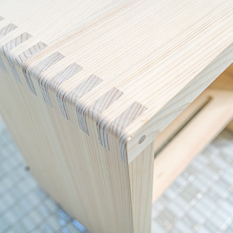 Close-up of a Japanese hinoki wood bath stool, showcasing precise joinery and natural wood grain, highlighting its craftsmanship and durability.