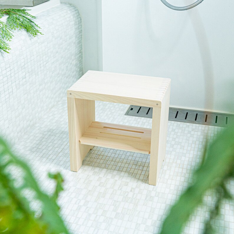 Elegant Japanese hinoki wood bath stool, crafted with precision joinery, set in a serene bathroom with natural accents and tiled surfaces.