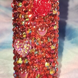 Könnte beinhalten: Roter Feuerzeugüberzug mit Strasssteinen und roten Rosen- und Herzverzierungen.