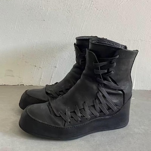 May include: A pair of black leather ankle boots with a unique design. The boots feature a lace-up closure and a thick, rounded sole. The uppers are made of a soft, textured leather, and the boots have a stacked heel.