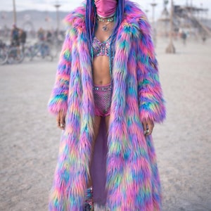 May include: A white ceramic mug with a black handle and the text "But First, Coffee" in a black, handwritten-style font. The mug is on a wooden surface.