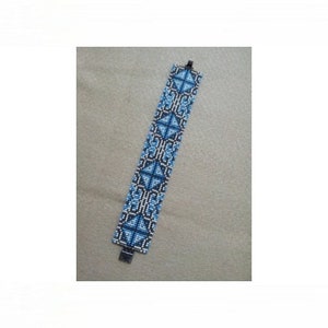 May include: A blue and white beaded bracelet with a geometric pattern. The bracelet is made with small, round beads and has a silver clasp.