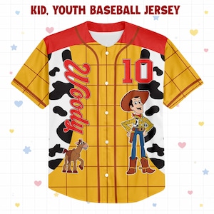 Op de afbeelding: Een geel honkbalshirt met een rode kraag en mouwen, met een stripfiguur en de naam "Woody". Het shirt heeft het nummer "10" op de voorkant en een koeienhuidpatroon.