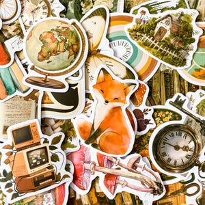 K&ouml;nnte beinhalten: Eine Sammlung von Stickern im Vintage-Stil mit einem Globus, einem Schmetterling, einem Fuchs, einer Uhr, einem Haus, Pilzen und einem Schl&uuml;ssel. Die Sticker sind auf wei&szlig;em Papier mit verschiedenen Farben und Designs gedruckt.