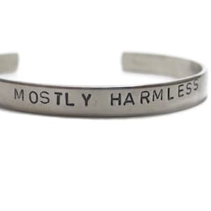 May include: A silver bracelet with the words "MOSTLY HARMLESS" engraved on it.