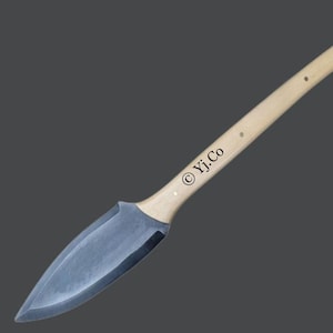 May include: A long, curved knife featuring a light wood handle and a dark, pointed blade. The handle has small, dark rivets and the text "© Yj.Co" printed on it. The blade is a dark grey colour.