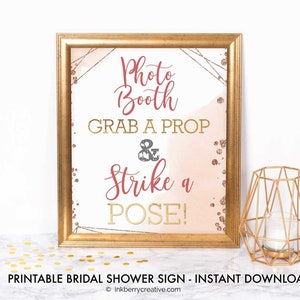 Peut inclure: Affiche imprimable pour un photobooth de mariage avec un fond aquarelle rose et or. L'affiche indique "Photo Booth Prenez un accessoire et posez !"