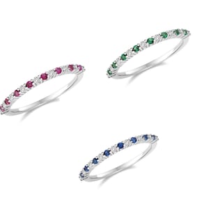以下が含まれることがあります： 小さな宝石が並んだ、繊細な銀の指輪が3つ。指輪は、ダイヤモンドと色のついた宝石が交互に並んだ1列のデザインです。赤いルビー、緑のエメラルド、青いサファイアです。