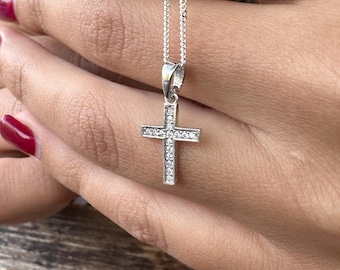 May include: A silver chain necklace with a small, silver cross pendant. The cross is encrusted with clear cubic zirconia stones.
