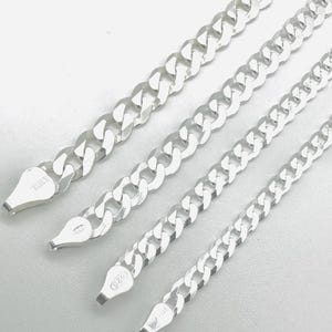 May include: Four silver curb chain necklaces of varying lengths are displayed against a white background. The chains have a classic, rounded link design. The clasps are visible, with markings indicating origin and metal purity.