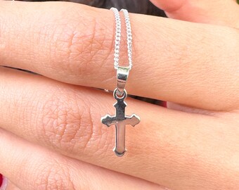 May include: A silver chain necklace with a small, silver cross pendant.