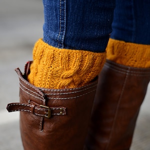 May include: Brown leather boots with a buckle and yellow knitted leg warmers.