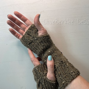May include: A pair of brown fingerless gloves with a textured knit pattern. The gloves are made with a speckled yarn and have a long cuff.
