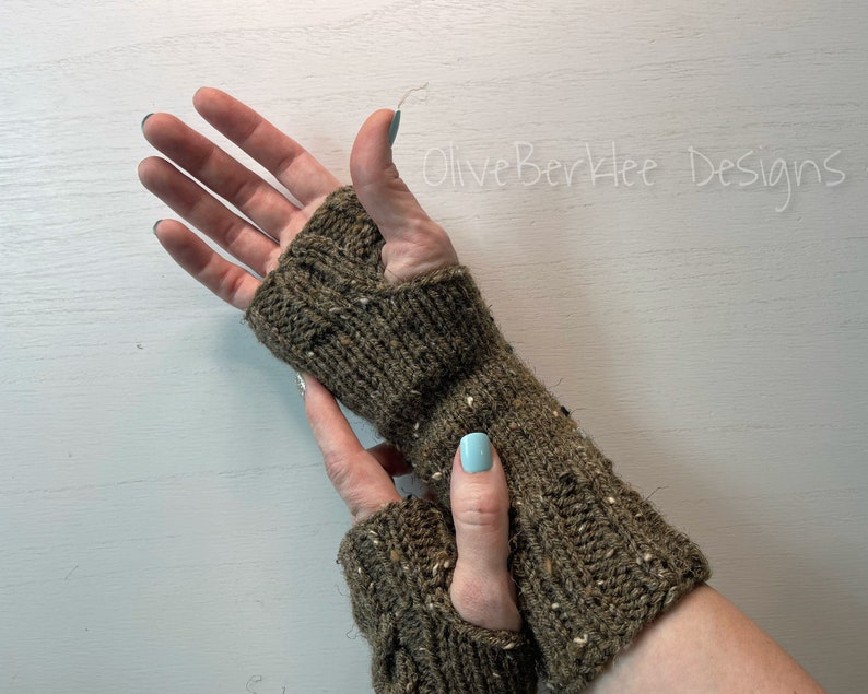 May include: A pair of brown fingerless gloves with a textured knit pattern. The gloves are made with a speckled yarn and have a long cuff.