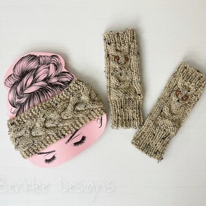 May include: Two pairs of beige knitted fingerless gloves with owl designs. The owls have brown button eyes. One pair of gloves is on a pink background with a drawing of a woman's hair.
