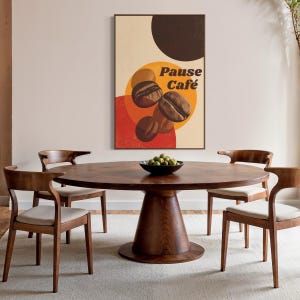 May include: A round, dark wood dining table with a pedestal base, surrounded by four wooden chairs with cream-colored seats. A framed poster with the words "Pause Café" and coffee bean illustrations hangs on the wall. A black bowl with green fruit sits on the table.