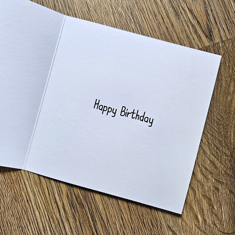 Peut inclure: Une carte blanche avec le texte "Happy Birthday" &eacute;crit en encre noire.