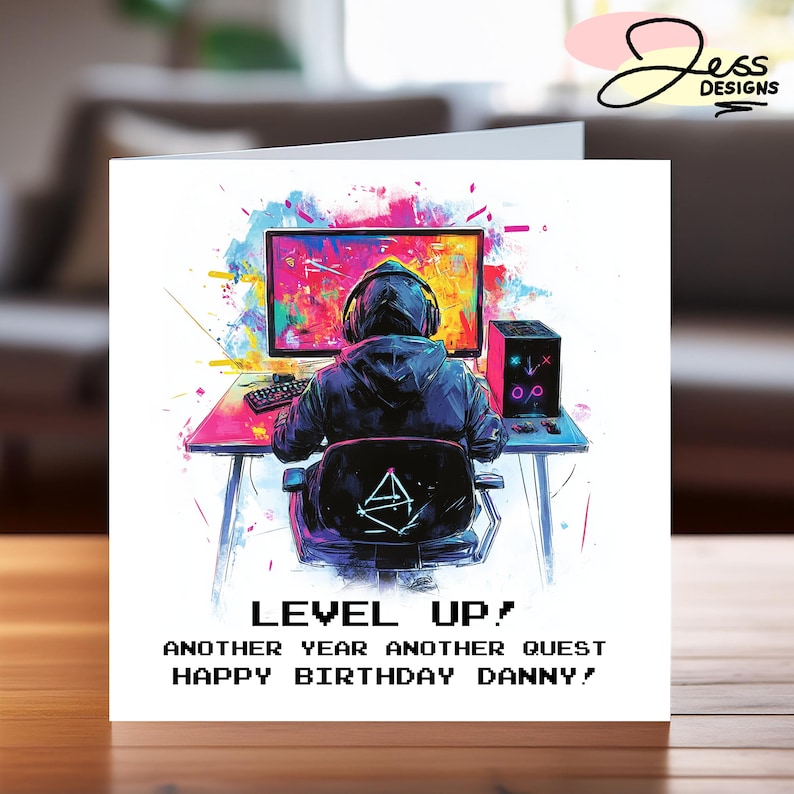 Peut inclure: Une carte d'anniversaire sur le th&egrave;me du jeu vid&eacute;o. La carte pr&eacute;sente une illustration color&eacute;e d'une personne jouant &agrave; un jeu vid&eacute;o sur un ordinateur. Le texte sur la carte est "Level Up! Another year another quest Happy Birthday Danny!"