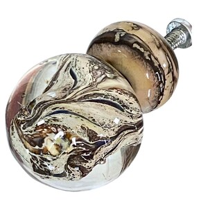 Könnte beinhalten: Ein brauner und weißer Glas-Schrankknauf mit einem Wirbelmuster. Der Knauf hat eine silberne Schraube.