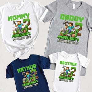 May include: A collection of Minecraft-themed shirts and a onesie. The shirts are white, gray, and navy blue, with green text that reads "Mommy", "Daddy", "Arthur", and "Brother". Each shirt features a Minecraft character and the text "The Minecraft Birthday Boy". A navy blue baseball cap is also present.