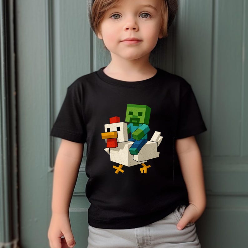 May include: Black t-shirt featuring a pixelated graphic of a zombie riding a chicken. The zombie is green and blue, and the chicken is white with a red comb and yellow feet. The design is centered on the shirt.