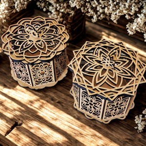 May include: Two decorative wooden boxes with intricate floral and geometric cut-out designs. The boxes are light brown with dark brown accents, and sit on a wooden surface. The lids and sides feature detailed patterns, creating a layered effect.