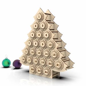 Puede incluir: Calendario de Adviento de madera con forma de árbol de Navidad, con 24 compartimentos numerados. El árbol es de madera clara y tiene un diseño en capas. Dos adornos navideños, uno verde y otro morado, están junto al árbol.