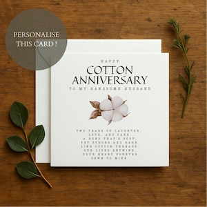 May include: A white anniversary card with the text "HAPPY COTTON ANNIVERSARY" and a cotton flower illustration. The card reads "TO MY HANDSOME HUSBAND" and includes a poem about love. The card is on a wooden surface.