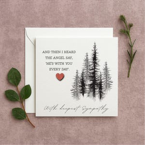 Può includere: Biglietto di condoglianze bianco con un'illustrazione in bianco e nero di pini e il testo "AND THEN I HEARD THE ANGEL SAY, 'HE'S WITH YOU EVERY DAY'." Un piccolo cuore rosso è attaccato, con le parole "With deepest Sympathy".