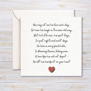 May include: A cream-coloured greeting card with an envelope. The card features a poem in black script on a textured, off-white surface. A small, red heart is at the bottom. The poem is about remembrance and love.