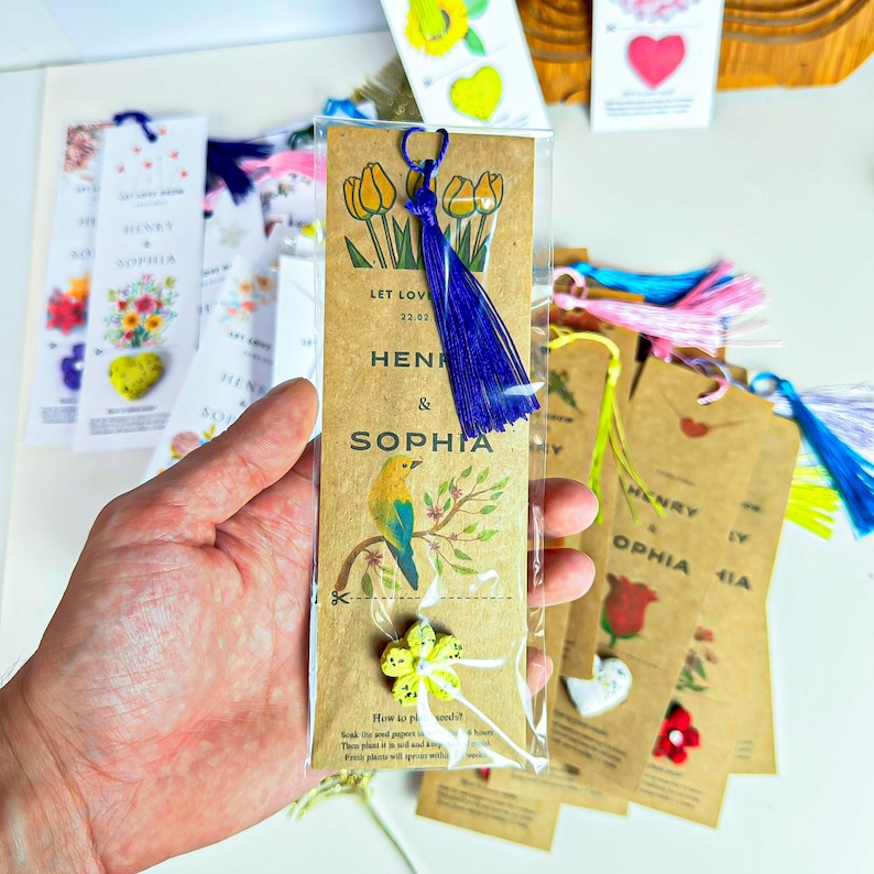 A collection of personalized bookmarks. The bookmarks are brown with printed text and illustrations. One bookmark features a blue tassel and a yellow flower. The text on the bookmarks includes names like Henry and Sophia, and phrases like 'Let Love'. Other bookmarks have heart and flower designs.