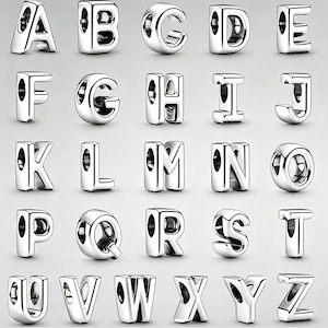 Può includere: Una collezione di ventisei ciondoli individuali a forma di lettere dell'alfabeto in metallo color argento. Ogni ciondolo presenta una superficie lucida e riflettente con un foro centrale cavo progettato per essere infilato su un bracciale.