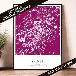May include: A framed map print of Gap, France, in magenta and white. The city's layout is detailed, showing streets and buildings. The text "GAP FRANCE 44.5596° N, 6.0787° E" is at the bottom. The words "MULTIPLE COLOUR SCHEMES" and "ANY CITY/TOWN" are also visible.
