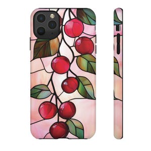 May include: A phone case featuring a stained-glass design of red cherries and green leaves on a pink background. The case has a black camera module and a matching design on the side.