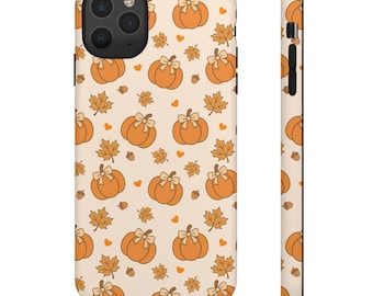 Puede incluir: Funda de teléfono beige con un patrón repetido de calabazas naranjas con lazos blancos, hojas de arce, bellotas y pequeños corazones naranjas. La funda tiene un recorte negro para la cámara y un borde negro.