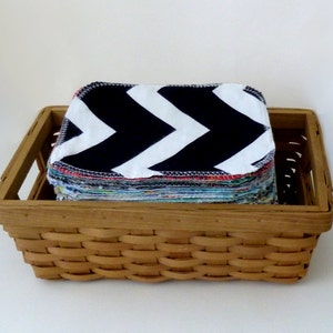 May include: A woven basket filled with a stack of black and white chevron patterned reusable makeup remover pads.