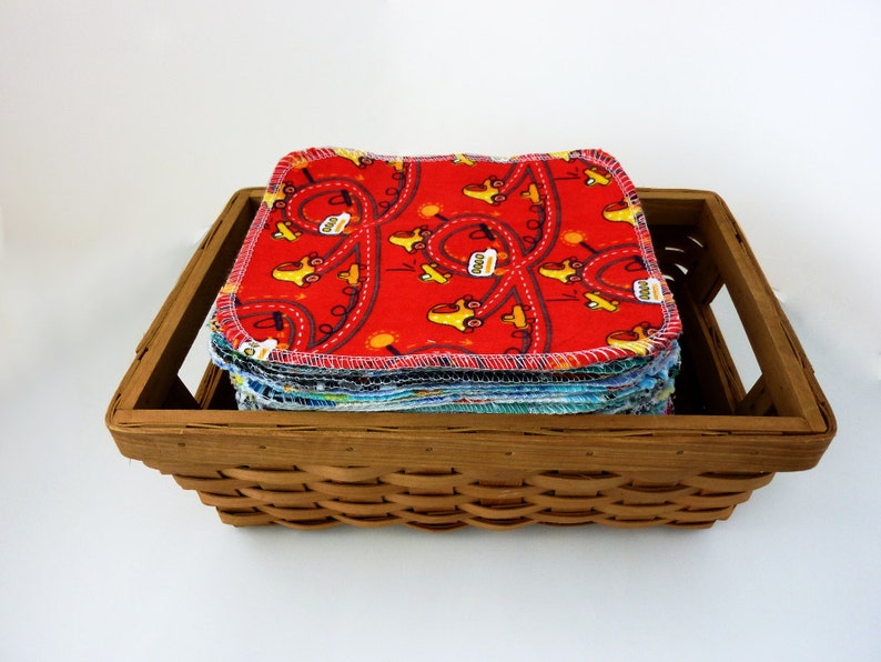 Puede incluir: Una pila de toallitas de tela reutilizables de color rojo, azul y amarillo con un patr&oacute;n de coche en una cesta de mimbre marr&oacute;n.