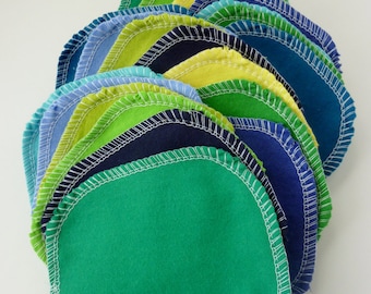 Puede incluir: Una pila de 15 círculos de tela redondos en varios tonos de verde, azul y amarillo. Los círculos están cosidos juntos con hilo blanco, creando un efecto de capas.