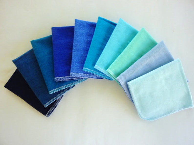 A fan shape of 10 paperless  towels in an ombre of blue solid colors from dark to light.  Navy, midnight blue, dark teal, royal blue, oxford blue, powder blue, electric blue, aqua, light blue, baby blue.