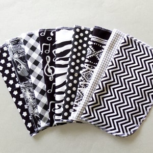 May include: A set of ten black and white fabric squares with different patterns, including musical notes, polka dots, stripes, and geometric designs.