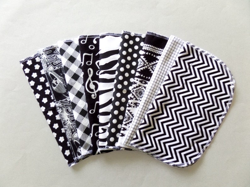 May include: A set of ten black and white fabric squares with different patterns, including musical notes, polka dots, stripes, and geometric designs.