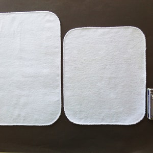 A sizing guide for paperless paper towels.  12 by 14 inch size is next to 12 by 10 inch size, by a deck of playing cards.  Lengthwise, the large size is 3 times the height of the cards.  The smaller size is 2 and a half times the height of the cards.
