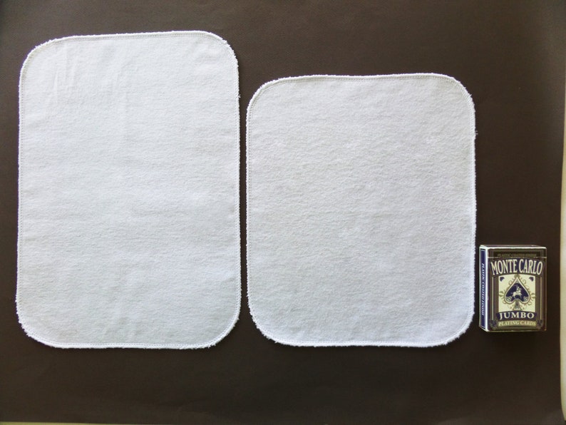 A sizing guide for paperless paper towels.  12 by 14 inch size is next to 12 by 10 inch size, by a deck of playing cards.  Lengthwise, the large size is 3 times the height of the cards.  The smaller size is 2 and a half times the height of the cards.