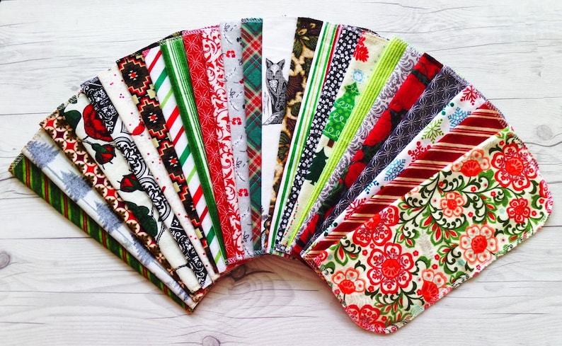May include: A collection of 20 fabric squares with various Christmas-themed patterns, including red and green stripes, snowflakes, and floral designs.