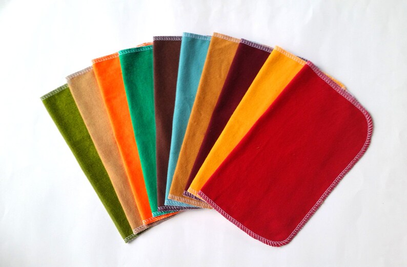 May include: A set of ten fabric swatches in various colors, including green, orange, brown, blue, yellow, and red. The swatches are arranged in a fan shape, with the red swatch at the bottom.
