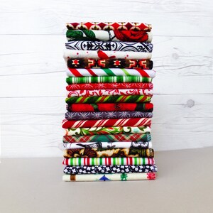 May include: A stack of 18 fabric squares with various Christmas-themed patterns, including red and white candy canes, snowflakes, and plaid.