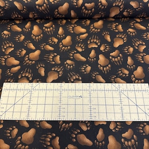 100 percent cotton fabric Bear Tracks on Black Background. Quantity 1= fat quarter. Greater than 1 is a continuous cut.