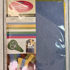 May include: A package of kraft-tex paper fabric in various colors, including denim, saffron, and emerald. The package includes prewashed sheets, 8.5" x 11", and features the text "Tough, touchable new paper" and "Combines the best of leather & fabric."