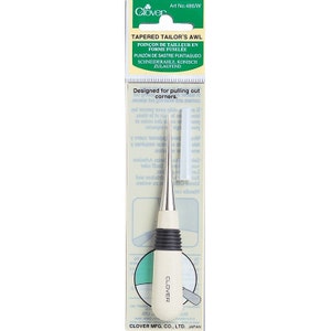 May include: A white and silver tapered tailor's awl with a black rubber grip. The awl is designed for pulling out corners. The packaging is green and white with the text "Clover" and "Tapered Tailor's Awl" in black.